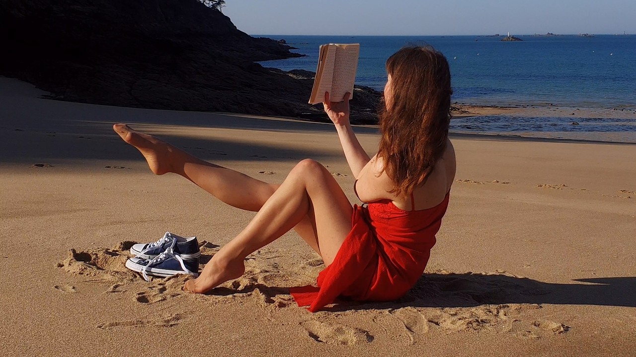 A girl in pantyhose reading at the beach