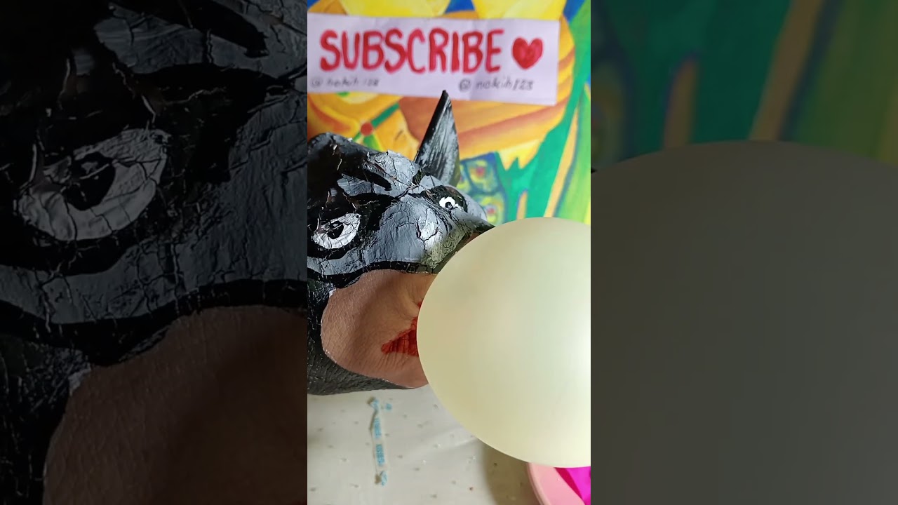 Batman hand blowing a yellow balloon.