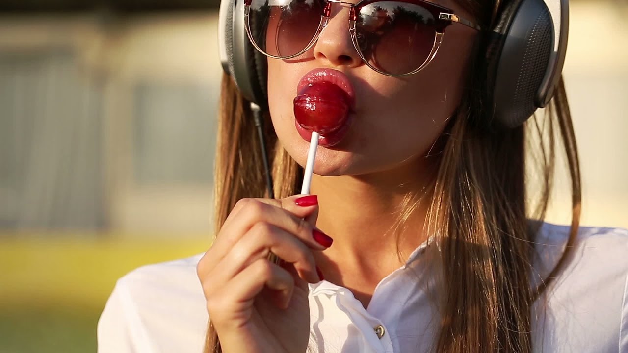 Girl licking lollipop and listening to music