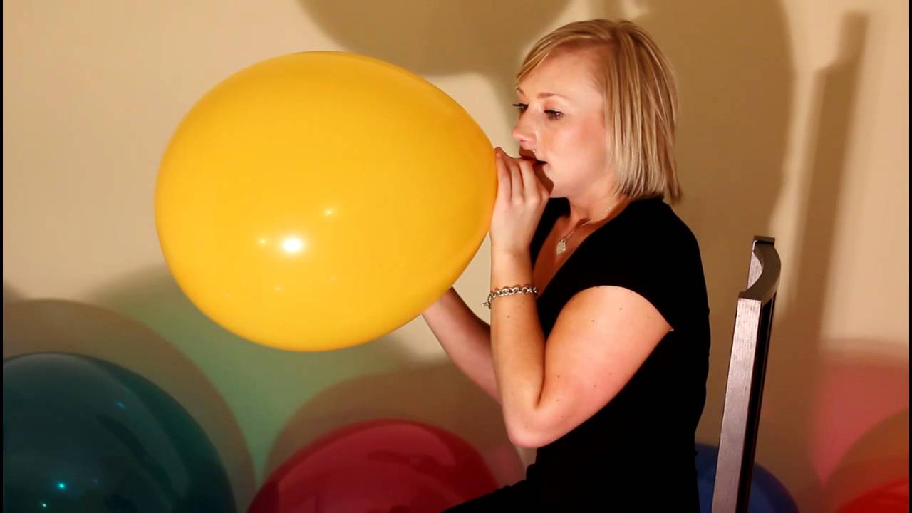 Kourtney blowing up a yellow balloon until it pops. - clips4sale.com/studio/45940