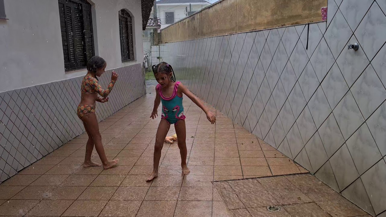 Laura com a prima Flávia tomando banho de chuva com granizo