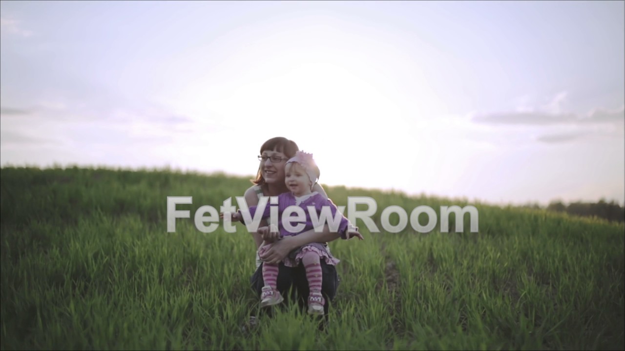 Little girl is sitting on the lap of mom outdoors