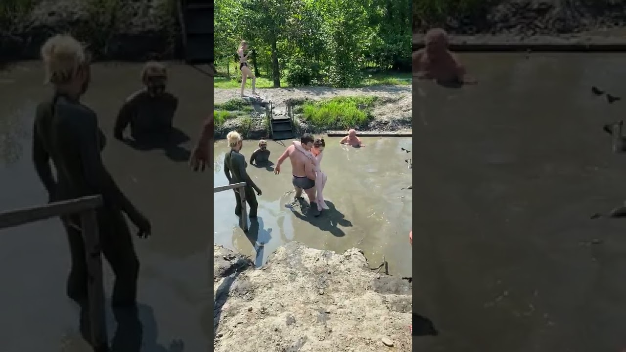 Man helps a disabled woman into a mud bath.
