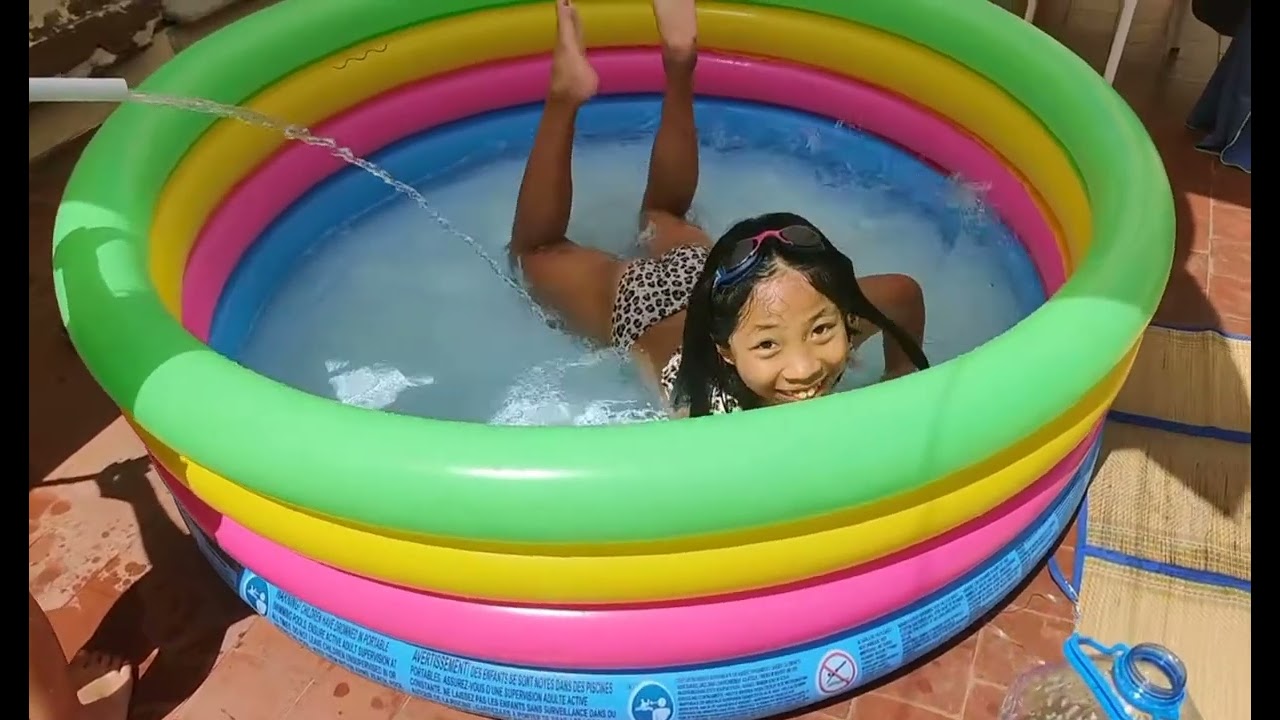 Menina brincando na piscina com a irmãzinha.