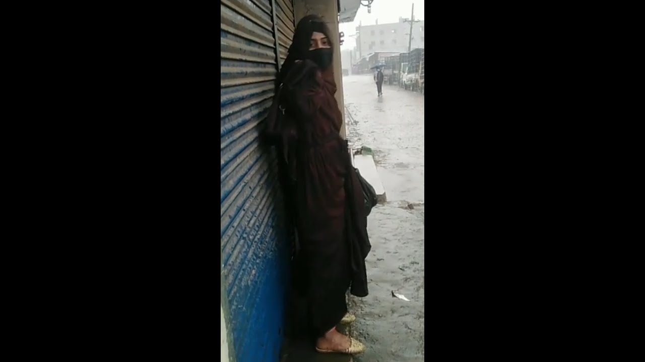 The girl wearing hijab is getting wet in the rain
