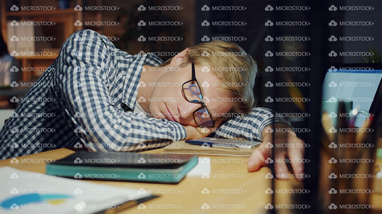 Tired businessman relaxing in office sleeping on desk in dark room at night