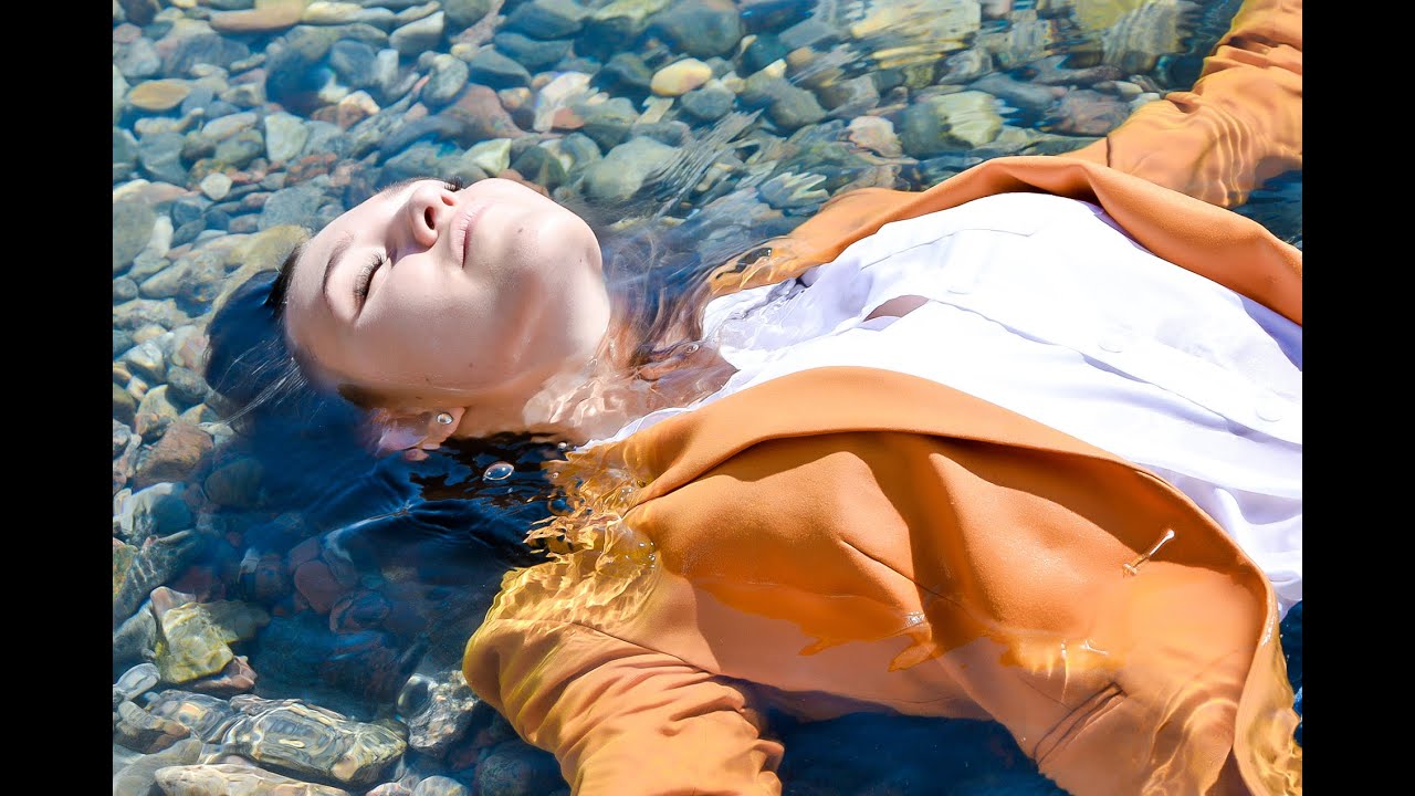 young girl in wet clothes poses tenderly on the beach by the sea for wetlook video